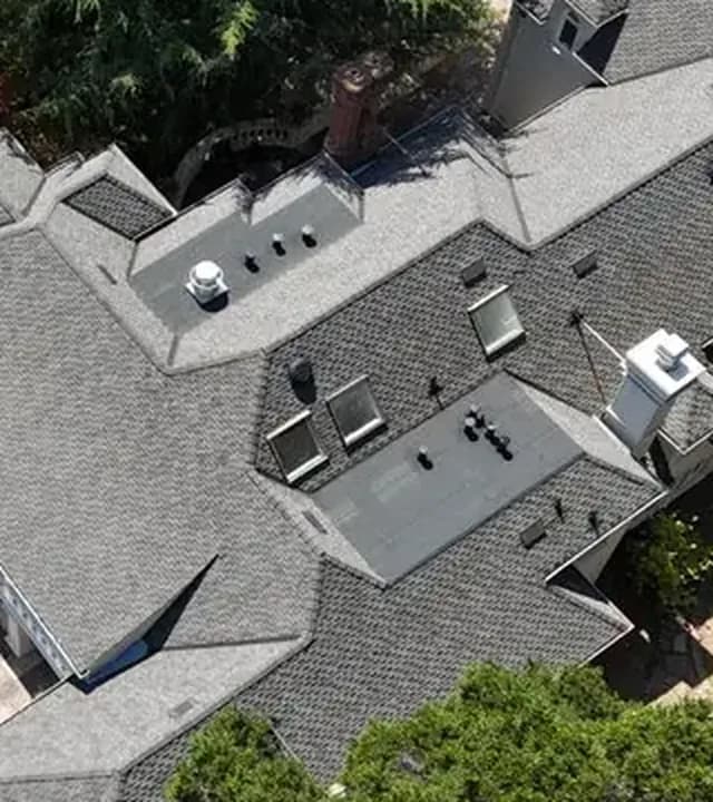 New gray architectural shingle roof seen from above, with ridges, chimneys and skylights